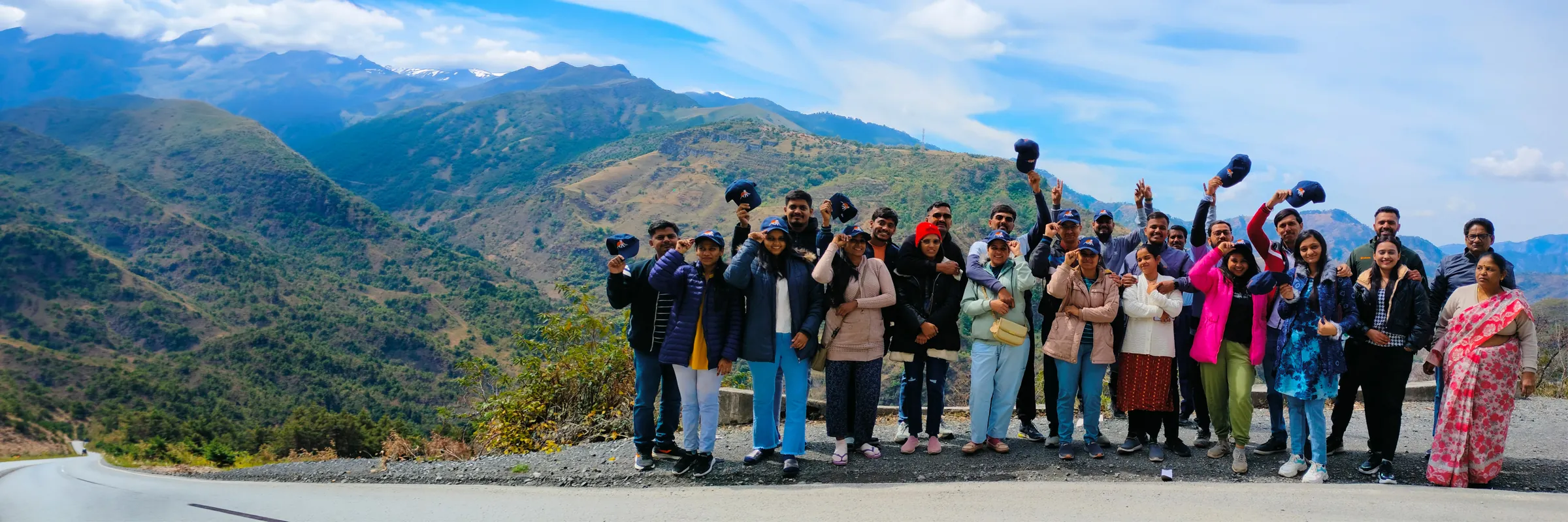 Kinghills group of travellers waving caps on a mountain road